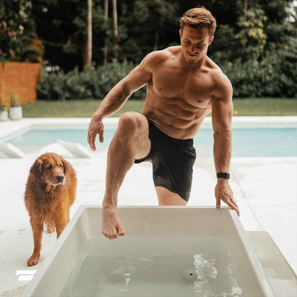 man stepping into plunge bath with dog next to him